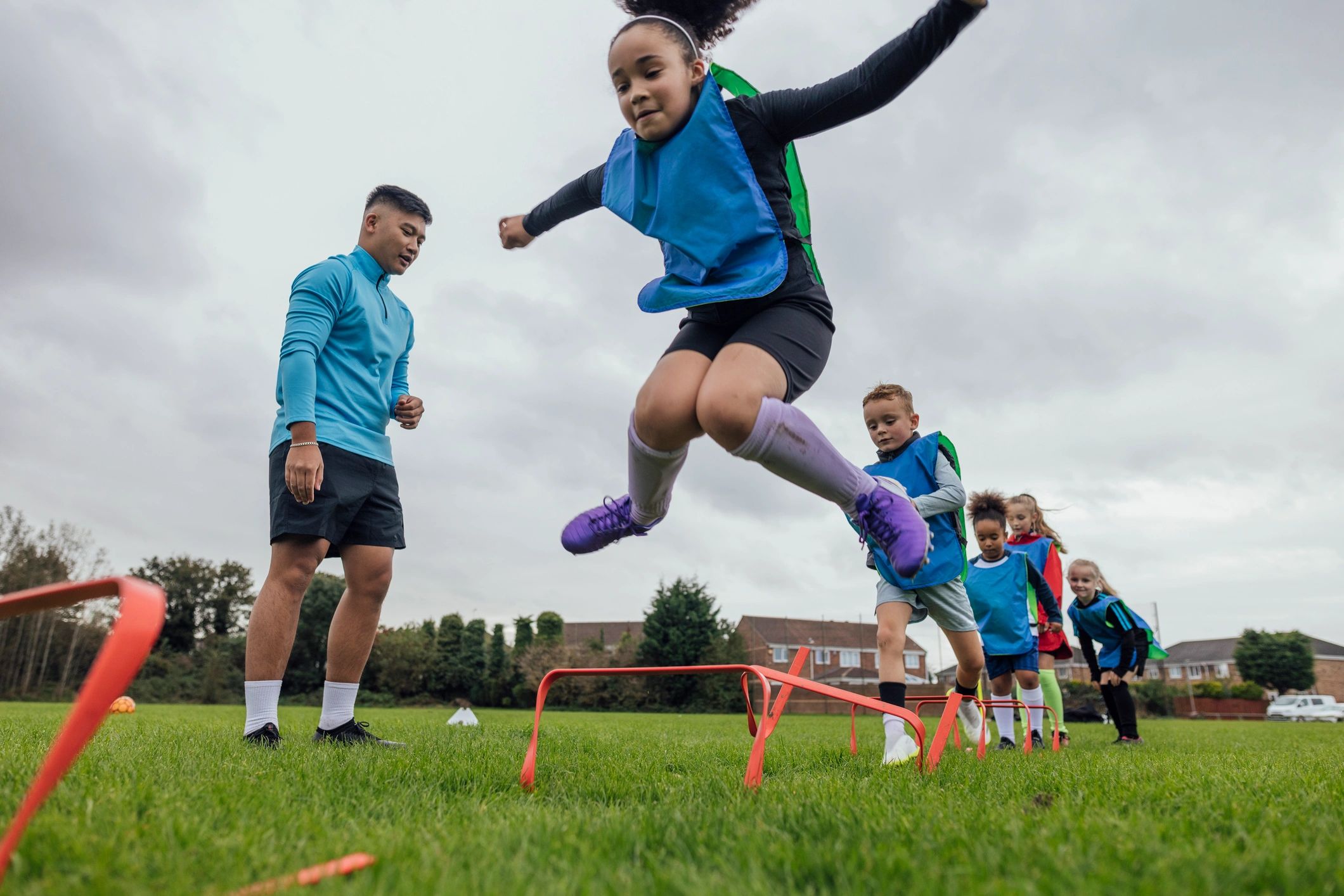Coach motivating athletes during agility hurdle drills