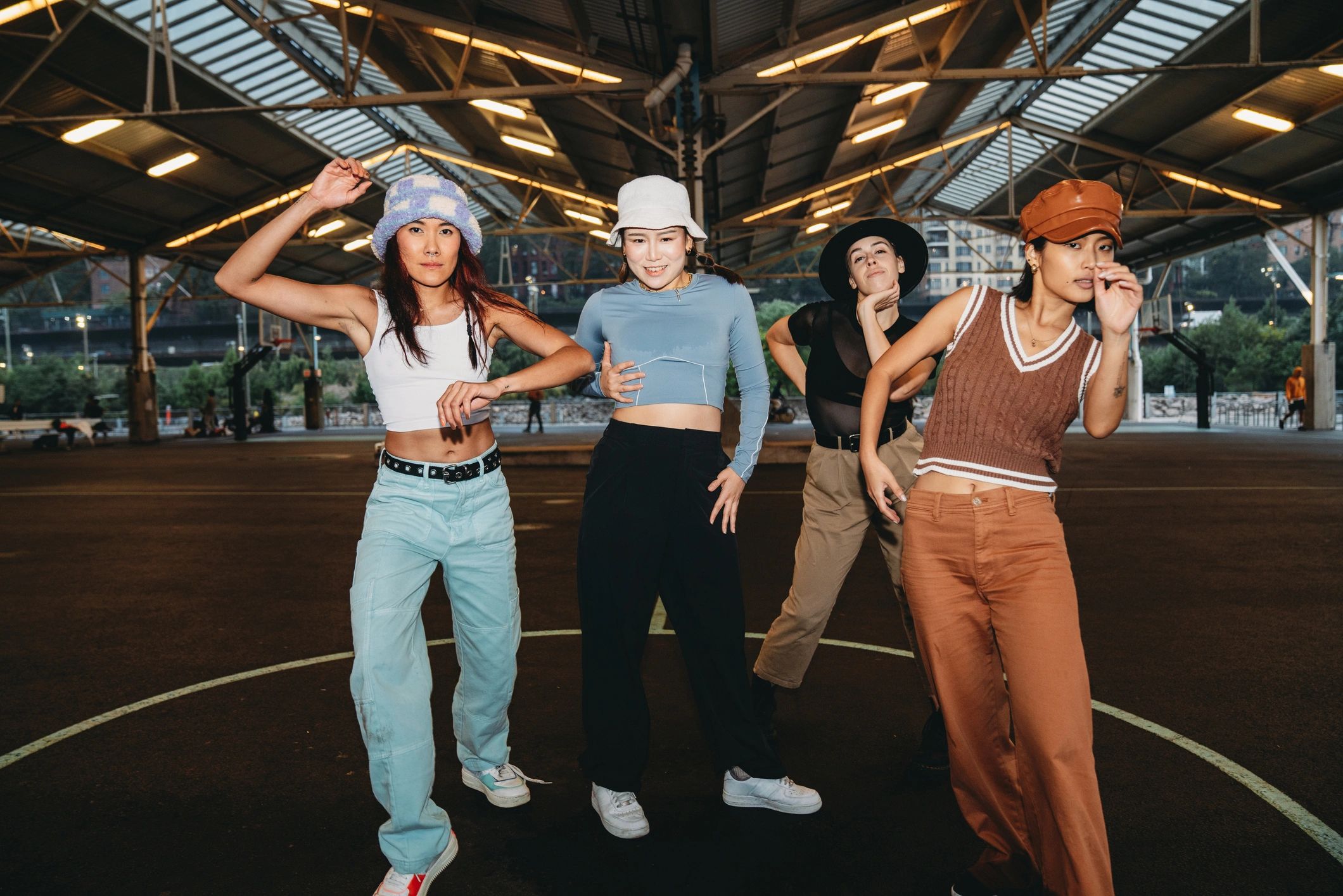 Young women in sporty streetwear dancing on a basketball court